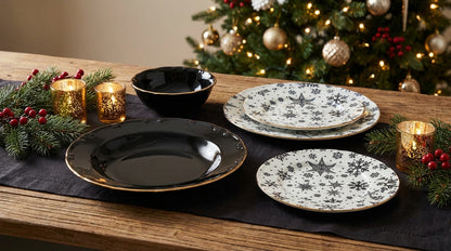 Dinnerware set on a table with Christmas decorations including a tree and candles.