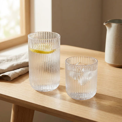Two clear glass tumblers on a wooden surface with a light background