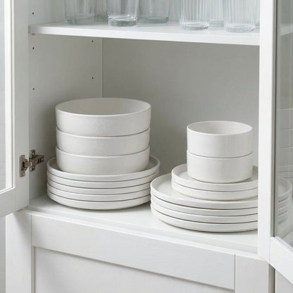 White ceramic bowls and plates stacked inside a white cabinet.