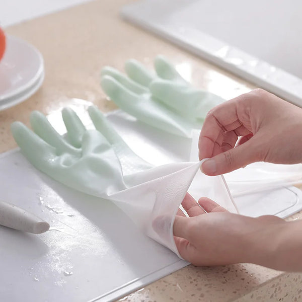 Person putting on a green rubber glove on a kitchen counter.