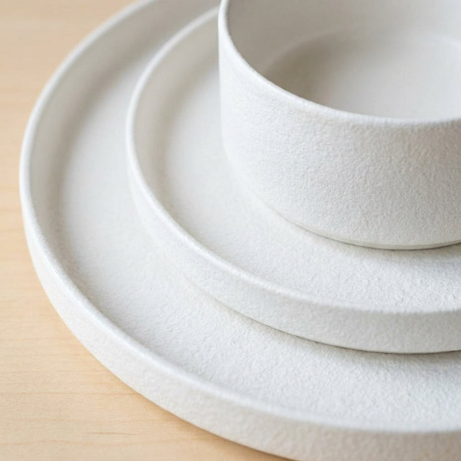 Stack of white ceramic plates on a beige surface