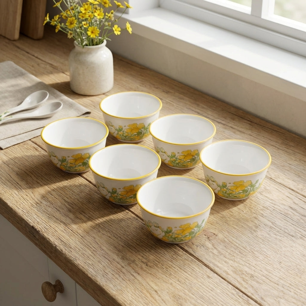 Set of ceramic bowls with floral design on a wooden surface near a window.