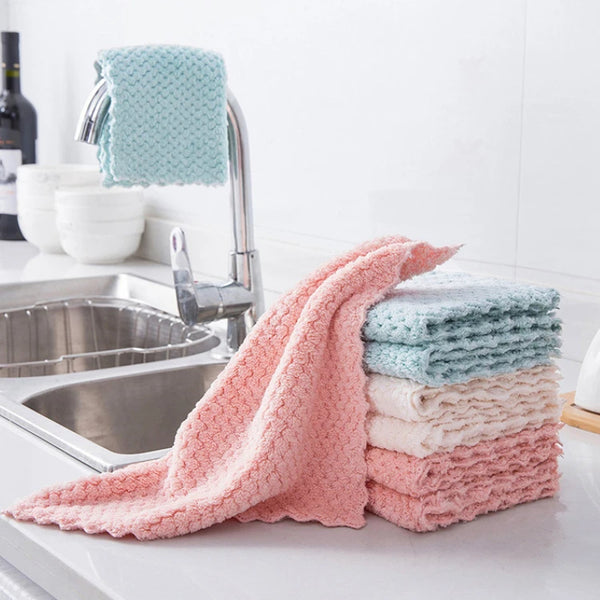 Stack of colorful kitchen towels on a kitchen counter with a sink in the background.