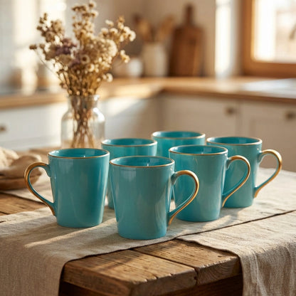 Set of turquoise mugs on a wooden table with a kitchen background
