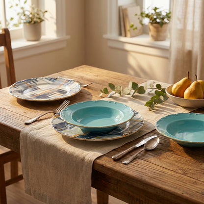 Dining table set with blue ceramic plates, silverware, and a bowl of pears in a bright room.