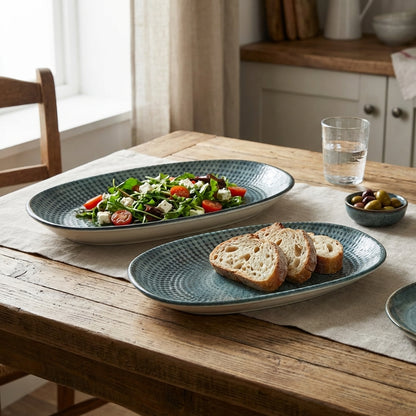 Dining table with plates of food including salad and bread, glass of water, and bowl of olives.