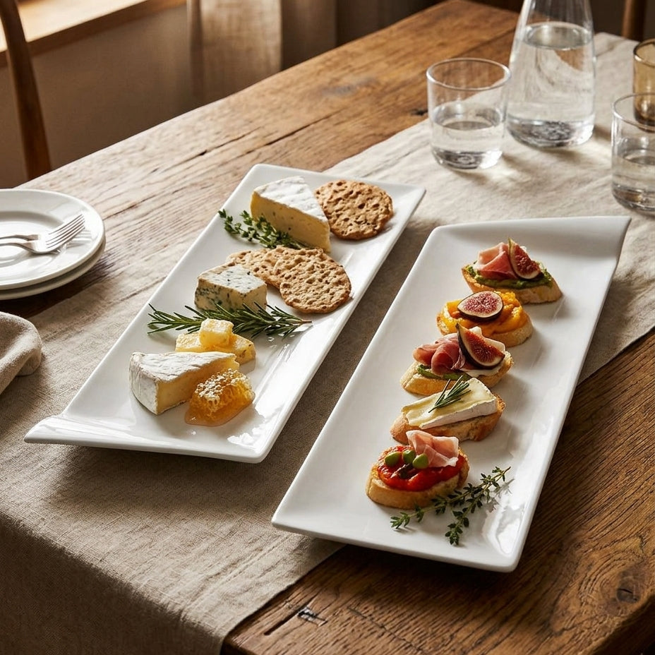 Two white platters with appetizers on a wooden table.