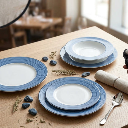Blue and white ceramic plates on a wooden table with a person using a smartphone.