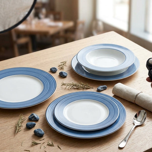 Blue and white ceramic plates on a wooden table with a person using a smartphone.