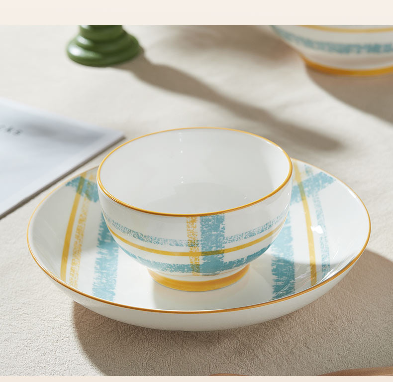 Ceramic bowl with plaid pattern on a matching plate on a wooden surface