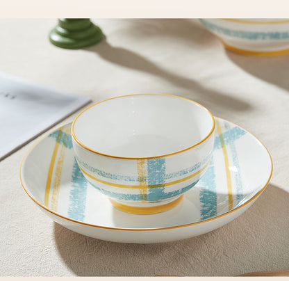 Ceramic bowl with plaid pattern on a matching plate on a wooden surface