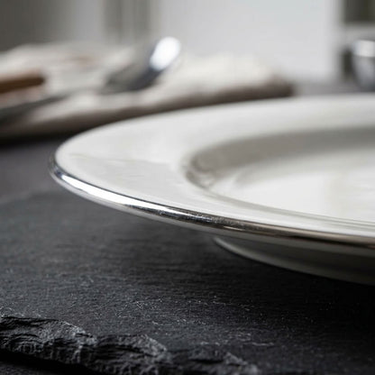 Stacked white oval serving platters with silver-tone rims
